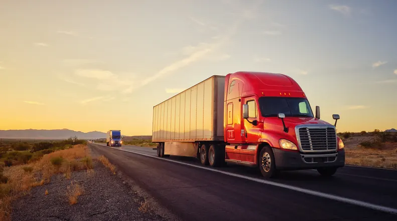 Fleet maintenance and scheduled PM programs — Bledsoe Truck & Trailer Repair, OKC Two Freightliner trucks traveling Oklahoma highway at sunset — Bledsoe Truck & Trailer Repair offers scheduled fleet maintenance programs for OKC owner-operators and small fleets.